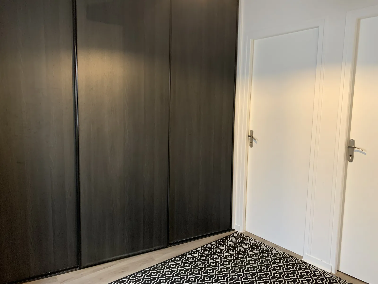 Entrée de l'appartement avec placards coulissants et tapis graphique